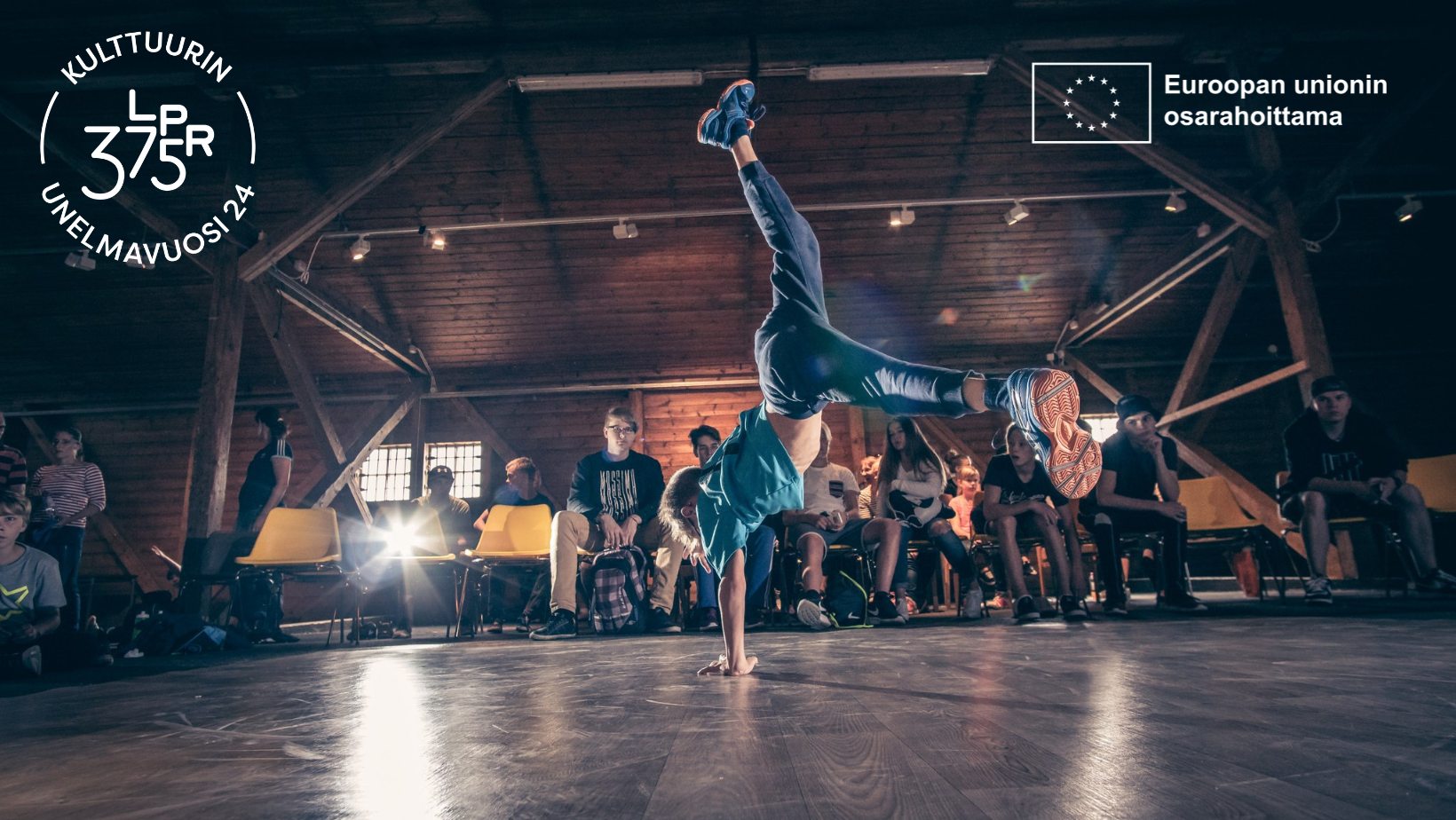 A boy is break dancing in front of the audience, there is logos of Lappeenranta Dream Year of Culture and Co-funded by European Union on the top corners.